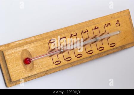 Raumthermometer auf einem Holzsockel, Nahaufnahme auf weißem Hintergrund. Grad Celsius. Stockfoto