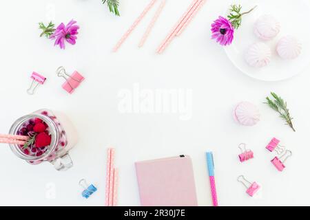 Schmackhafter Smoothie mit Strohhalmen, Marshmallow, Tagebuch, Stift und pinkfarbenen Blumen auf weißem Hintergrund. Flach verlegt. Stockfoto