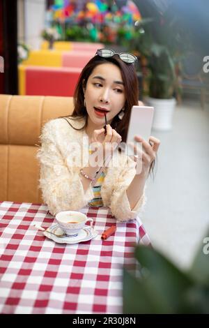 Schöne junge chinesische Frau, die Lippenstift anwendet Stockfoto