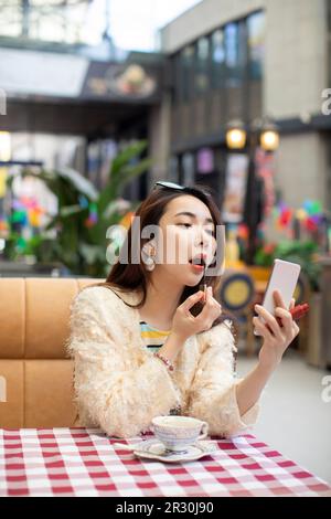 Schöne junge chinesische Frau, die Lippenstift anwendet Stockfoto