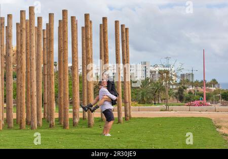 Ein Mann mittleren Alters mit Grizzles und weißem Bart hält seinen Partner mit Anstrengung. Er trägt Bermuda-Shorts und ein Hemd. Sie trägt Shorts und Knöchel Stockfoto