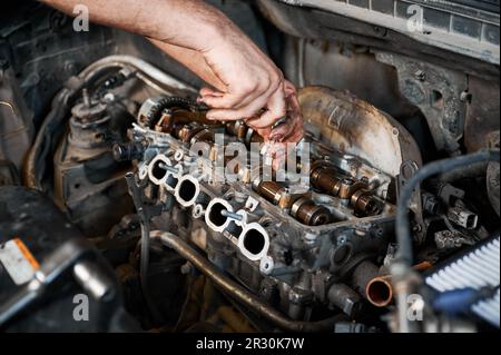 Nahaufnahme eines Mechanikers, der den Motor repariert, in der Garage, in der Werkstatt, im Kfz-Servicezentrum arbeitet. Arbeiter, Mechaniker mit Schraubenzieher. Konzept der Fahrzeugreparatur. Stockfoto