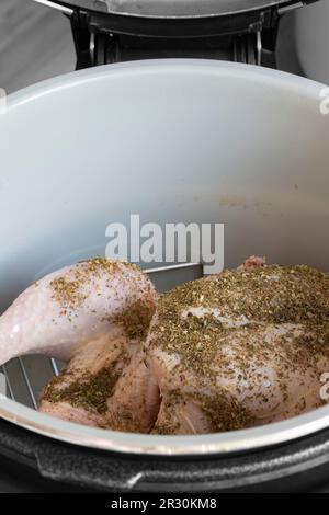 Rohes Hähnchen mit gemischten Kräutern auf einem Regal in einer Airfryer, das sich auf das Kochen vorbereitet. Gesundes, kostengünstiges Kochkonzept Stockfoto