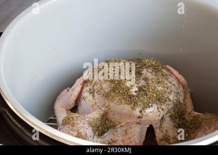 Rohes Hähnchen mit gemischten Kräutern auf einem Regal in einer Airfryer, das sich auf das Kochen vorbereitet. Gesundes, kostengünstiges Kochkonzept Stockfoto