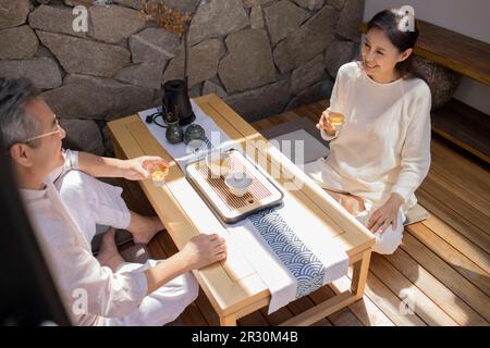 Glückliches, reifes chinesisches Paar, das Tee im Teezimmer trinkt Stockfoto