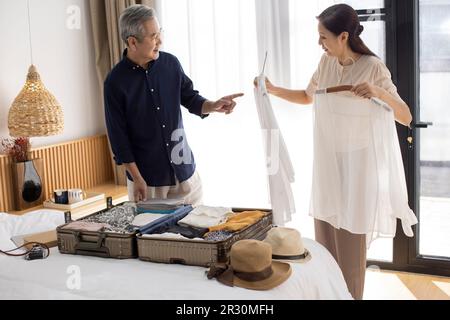 Glückliches reifes chinesisches Paar, das Koffer für den Urlaub packt Stockfoto