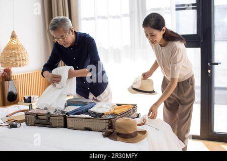 Glückliches reifes chinesisches Paar, das Koffer für den Urlaub packt Stockfoto