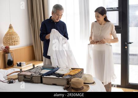 Glückliches reifes chinesisches Paar, das Koffer für den Urlaub packt Stockfoto