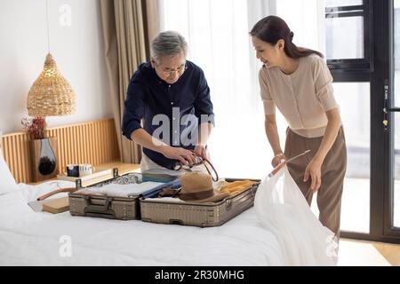 Glückliches reifes chinesisches Paar, das Koffer für den Urlaub packt Stockfoto
