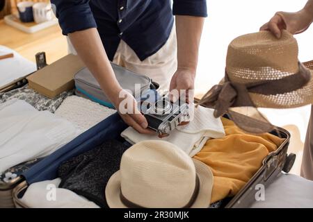 Glückliches reifes chinesisches Paar, das Koffer für den Urlaub packt Stockfoto
