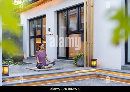 Reife Chinesin, die im Freien Yoga macht Stockfoto