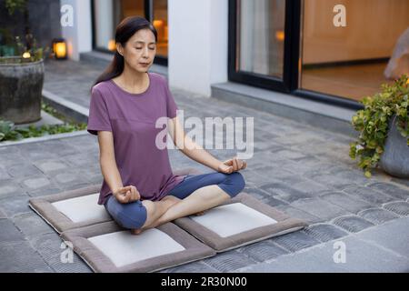 Reife Chinesin, die im Freien Yoga macht Stockfoto