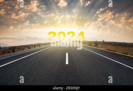 Starten Sie das Jahr 2024. Frohe Neujahrskarte. Schriftzug „Jahr 2024“ am Horizont mit leerer Asphaltstraße Stockfoto