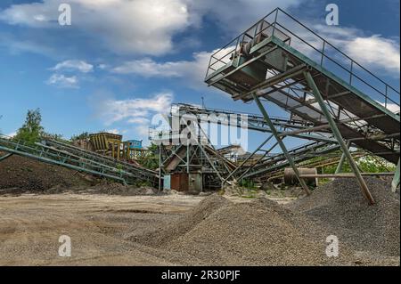 Steinbruchförderer für die Minningindustrie. Brechmaschinen, Kegelsteinbrecher, Förderer von zerdrücktem Granitkiesstein in einem Steinbruch-Minin Stockfoto