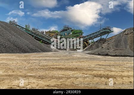 Steinbruchförderer für die Minningindustrie. Brechmaschinen, Kegelsteinbrecher, Förderer von zerdrücktem Granitkiesstein in einem Steinbruch-Minin Stockfoto