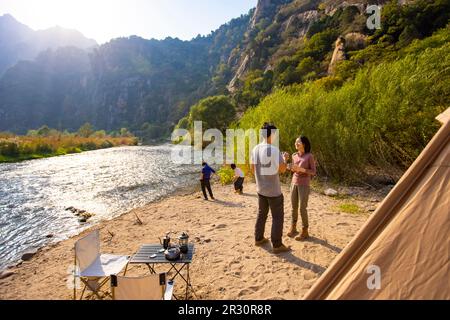 Glückliche junge chinesische Familie, die im Freien campen kann Stockfoto