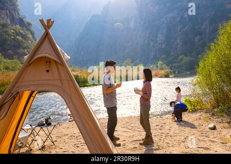 Glückliche junge chinesische Familie, die im Freien campen kann Stockfoto