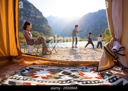 Glückliche junge chinesische Familie, die im Freien campen kann Stockfoto