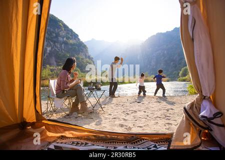 Glückliche junge chinesische Familie, die im Freien campen kann Stockfoto