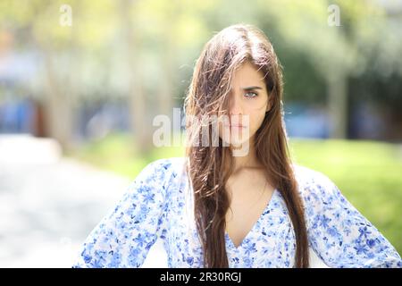 Wütende Frau mit touseltem Haar, ein windiger Tag, der auf der Straße in die Kamera schaut Stockfoto