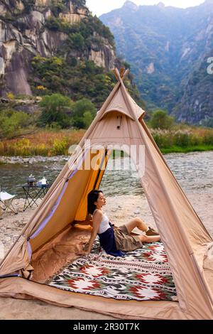 Junge Chinesin campen draußen Stockfoto