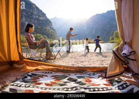 Glückliche junge chinesische Familie, die im Freien campen kann Stockfoto