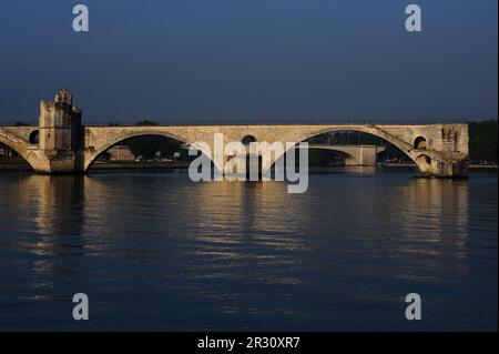 Pont d’Avignon oder Pont Saint-Bénézet, eine mittelalterliche Brücke über den Fluss Rhône in Avignon, Hauptstadt des Departements Vaucluse in der französischen Region Provence-Alpes-Côte-d’Azur. Auf der linken Seite befindet sich die Saint-Bénézet- oder St. Nicholas-Kapelle. Sowohl die Pont d'Avignon als auch ihre Kapelle wurden Ende der 1100s Jahre im provenzalischen romanischen Stil erbaut, obwohl die Kapelle später umgestaltet wurde. Die Brücke gehört zum UNESCO-Weltkulturerbe. Dieses Foto wurde an einem frühen Juli Morgen aufgenommen, zwischen 7am und 8am Uhr. Stockfoto