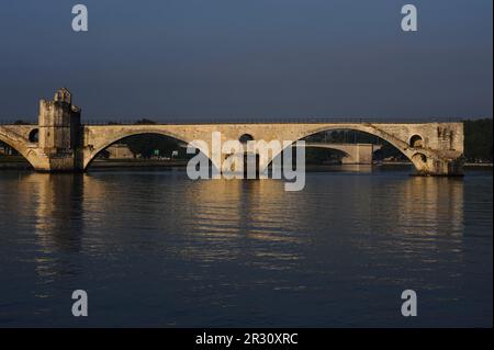 Mittelalterliche Pont d'Avignon oder Pont Saint-Bénézet über dem Fluss Rhône mit der Saint-Bénézet- oder Saint-Nicholas-Kapelle auf der linken Seite. Sowohl die Brücke als auch die Kapelle wurden Ende der 1100s Jahre im provenzalischen romanischen Stil erbaut, obwohl die Kapelle später umgestaltet wurde. In Avignon, Hauptstadt des Departements Vaucluse in der französischen Region Provence-Alpes-Côte-d’Azur. Die Brücke gehört zum UNESCO-Weltkulturerbe. Dieses Foto wurde an einem frühen Juli Morgen aufgenommen, zwischen 7am und 8am Uhr. Stockfoto