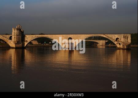 Die Pont d'Avignon oder Pont Saint-Bénézet, eine mittelalterliche Brücke über den Fluss Rhône, wurde in den späten 1100s Jahren im provenzalischen romanischen Stil erbaut. Auf der linken Seite befindet sich die Saint-Bénézet- oder St. Nicholas-Kapelle, die ebenfalls in den 1100s Jahren erbaut, aber später umgestaltet wurde. In Avignon, Hauptstadt des Departements Vaucluse in der französischen Region Provence-Alpes-Côte-d’Azur. Die Brücke gehört zum UNESCO-Weltkulturerbe. Dieses Foto wurde an einem frühen Juli Morgen aufgenommen, zwischen 7am und 8am Uhr. Stockfoto