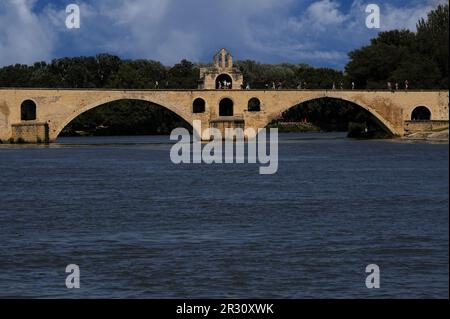 Touristen und Touristen an einem Juli Nachmittag auf der Pont d'Avignon oder Pont Saint-Bénézet, einer mittelalterlichen Brücke über den Fluss Rhône, mit einigen Stopps, um die Saint-Bénézet oder die St. Nicholas Kapelle zu sehen. Sowohl die Kapelle als auch die Brücke wurden Ende der 1100s Jahre im provenzalischen romanischen Stil gebaut, aber die Kapelle wurde später umgestaltet. In Avignon, Hauptstadt des Departements Vaucluse in der französischen Region Provence-Alpes-Côte-d’Azur. Stockfoto