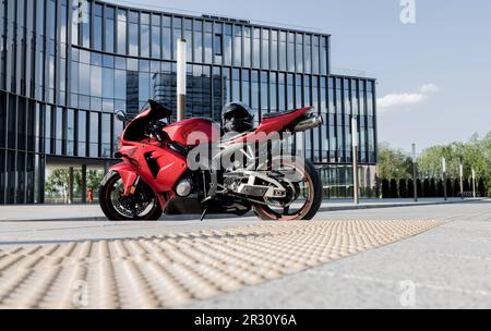 Minsk, Belarus, Mai 2023 - wunderschönes rotes Motorrad Honda in der Nähe eines Glasgebäudes Stockfoto