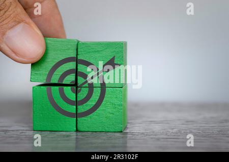 Mit der Hand platzierte Holzwürfel mit dem Symbol für das Zielbrett. Platz für Text kopieren. Geschäftsziel, Ziel, Zielkonzept Stockfoto