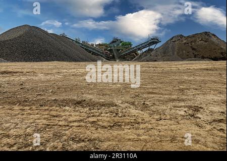 Steinbruchförderer für die Minningindustrie. Brechmaschinen, Kegelsteinbrecher, Förderer von zerdrücktem Granitkiesstein in einem Steinbruch-Minin Stockfoto