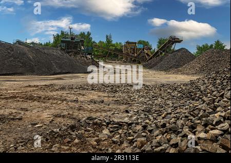 Steinbruchförderer für die Minningindustrie. Brechmaschinen, Kegelsteinbrecher, Förderer von zerdrücktem Granitkiesstein in einem Steinbruch-Minin Stockfoto