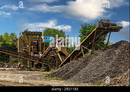 Steinbruchförderer für die Minningindustrie. Brechmaschinen, Kegelsteinbrecher, Förderer von zerdrücktem Granitkiesstein in einem Steinbruch-Minin Stockfoto