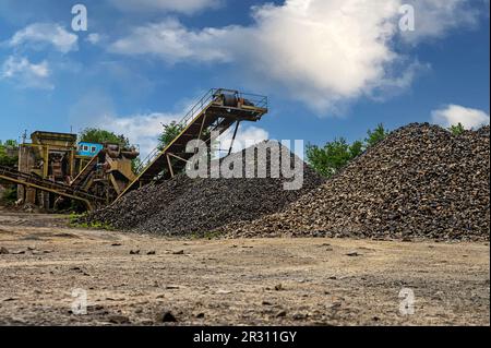 Steinbruchförderer für die Minningindustrie. Brechmaschinen, Kegelsteinbrecher, Förderer von zerdrücktem Granitkiesstein in einem Steinbruch-Minin Stockfoto