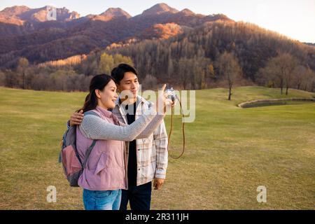 Glückliches junges Paar, das im Freien Fotos macht Stockfoto