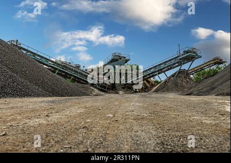 Steinbruchförderer für die Minningindustrie. Brechmaschinen, Kegelsteinbrecher, Förderer von zerdrücktem Granitkiesstein in einem Steinbruch-Minin Stockfoto