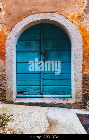 Alte verschlossene blaue Holztür mit Betonbogen, Details aus den Straßen von Lovran, Altstadt und Reiseziel in Kroatien Istrien Stockfoto