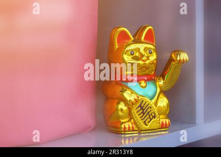 Maneki Neko, japanische Wunschkatze, schmückt die Ladenfront einer trendigen Boutique für Kleidung. Diese glückliche Katzenfigur ist ein beliebtes Symbol für Glück und Glück Stockfoto