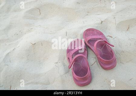 Pinke Sandalen am Sandstrand. Draufsicht, Kopierbereich. Stockfoto