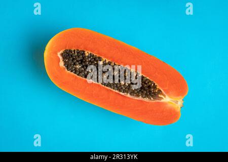 Reife Papaya-Früchte, halbiert auf blauem Hintergrund. Sommerzeitkonzept. Stockfoto