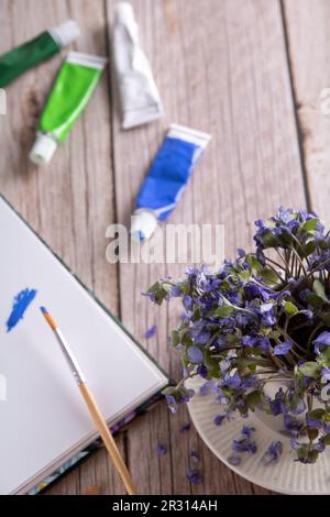 Fotofarbe, Pinsel, welkte Blumen in einer weißen Kaffeetasse, Draufsicht Stockfoto