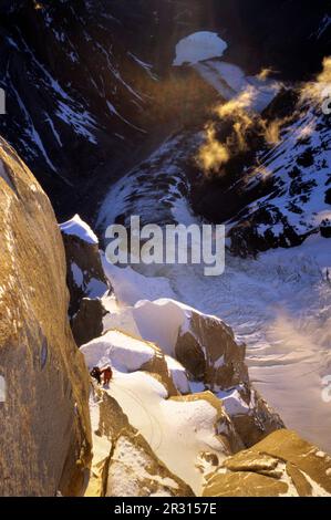 Zwei Bergsteiger halten bei Sonnenaufgang auf einem Vorsprung während des Abstiegs auf den südöstlichen Kamm des Cerro Torre in Argentinien Patagonien. Stockfoto
