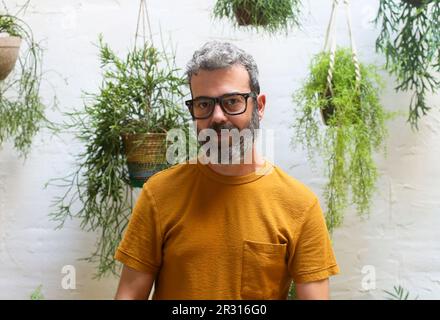 Porträt des Menschen vor hängenden Pflanzen auf der Terrasse. Stockfoto