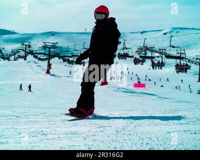 Snowboarder fährt auf der Strecke mit Seilbahn im Hintergrund Stockfoto
