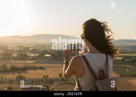 Eine junge Frau macht ein Foto mit ihrem Smartphone auf einem Berg Stockfoto