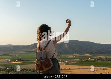 Eine junge Frau macht ein Selfie mit ihrem Smartphone auf dem Gipfel des Berges Stockfoto