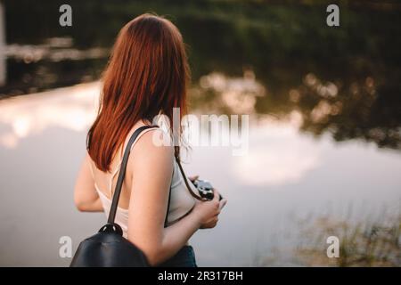 Eine Frau mit Kamera, die am See steht Stockfoto