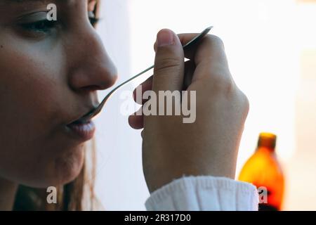 Gesundheit und Medizin - Junge Frau, die Hustensaft nimmt. Stockfoto